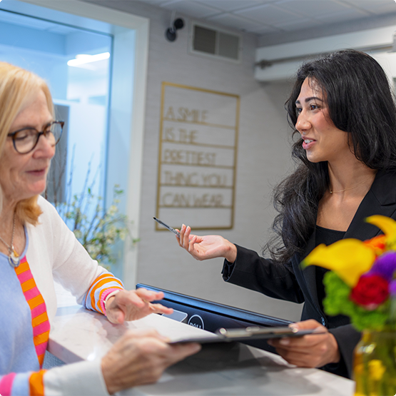 Woman talking to a dental team member about paperwork
