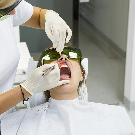 Woman in the dental chair being treated with a soft tissue laser
