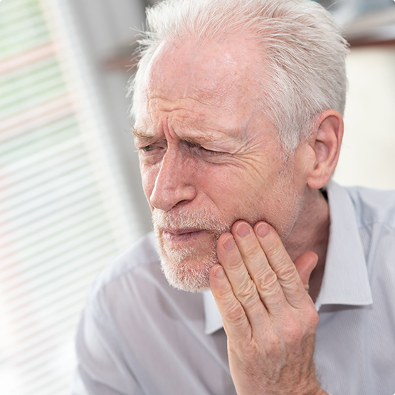 Older man holding his cheek in pain