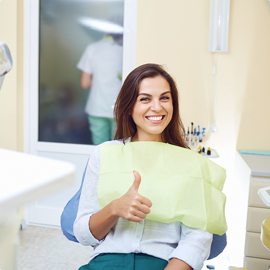 Woman smiling and giving a thumbs up in the dental chair