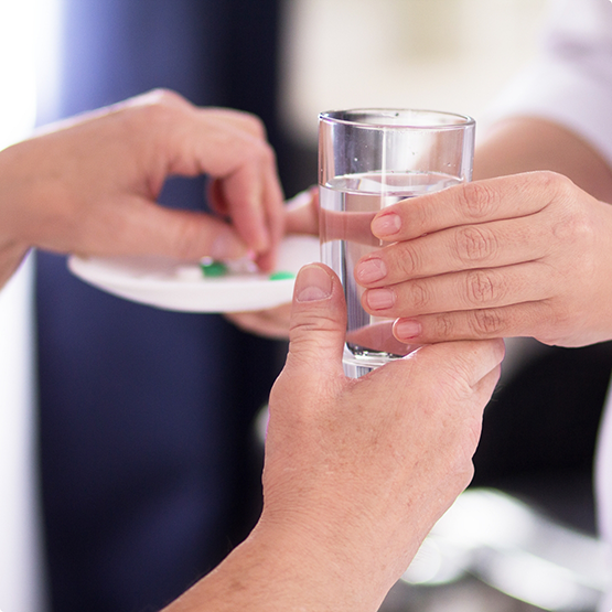 Medical professional handing a patient a pill and a glass of water
